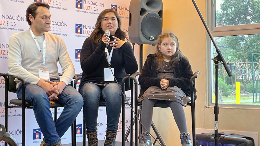 Marilyn Fuentes, mamá de María Paz, usuaria de Fundación luz, sentada en una silla con micrófono en mano hablando