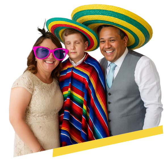 Tres personas posan frente a un fondo blanco, sonriendo con actitud festiva. A la izquierda, una mujer de cabello castaño claro lleva un vestido beige de encaje y gafas grandes de color fucsia. En el centro, un niño no vidente con cabello corto y claro viste una camisa blanca, un poncho multicolor y un sombrero mexicano. A la derecha, un hombre de tez media, cabello oscuro con canas y sonrisa amplia, lleva una camisa blanca con chaleco gris y corbata celeste. Todos lucen alegres y coloridos.