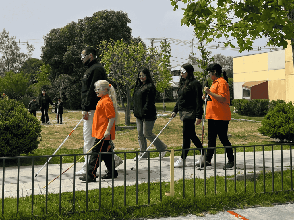 Estudiantes con discapacidad visual guiando a sus profesores por el colegio, hay una niña albina.