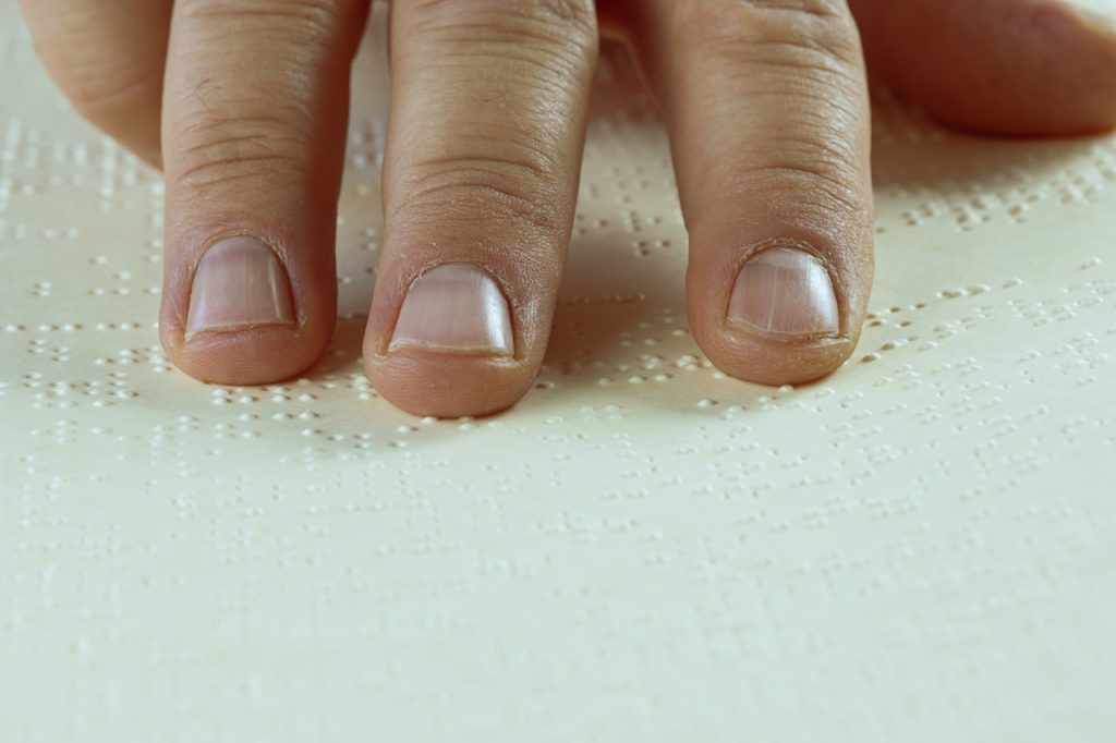 Dedos tocando letras en braille.