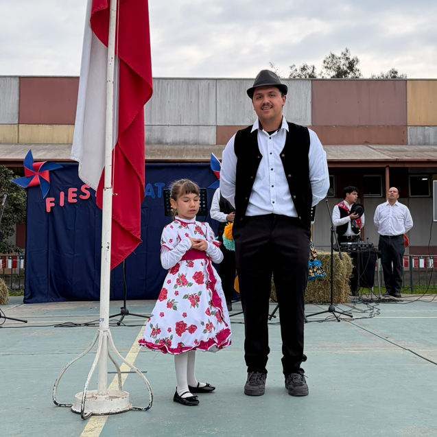 El kinesiólogo, Nicolás Acuña, junto a Anaís, beneficiaria de Fundación Luz, izando la bandera chilena.