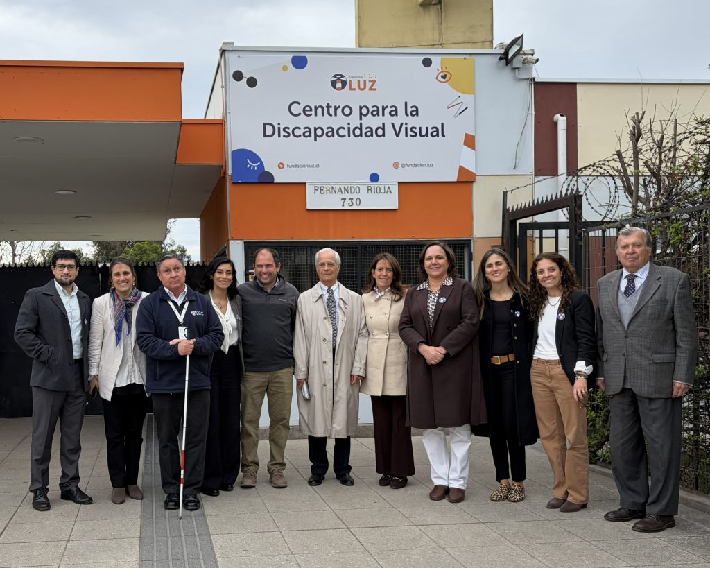 La Primera Dama, Pía Adriasola, posa sonriente junto al Directorio de Fundación Luz en el frontis de la sede La Cisterna.
